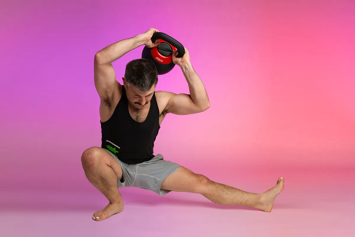 Ricky in a side lunge holding a kettlebell overhead.